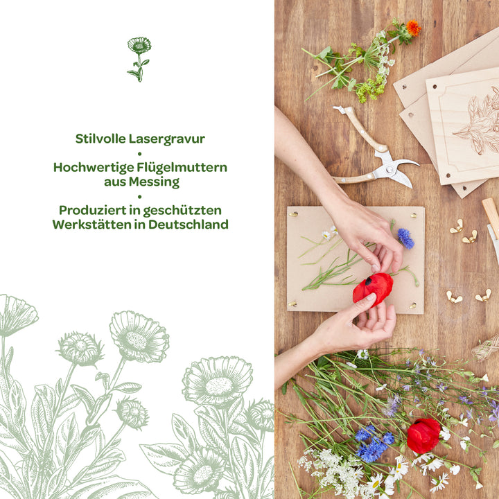 Zwei Hände arrangieren bunte Blumen auf einem Holzrahmen; daneben liegen Werkzeuge, Messing-Flügelmuttern und gravierte Holzplatten auf einem Holztisch. Links Text mit Informationen über stilvolle Lasergravur und Produktion in Deutschland.
