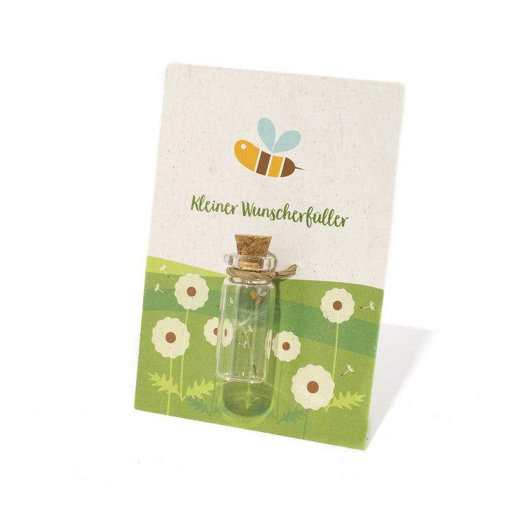 Kleine Glasflasche mit Korken auf einer dekorativen Karte mit Bienenmotiv und der Aufschrift "Kleiner Wunscherfüller".