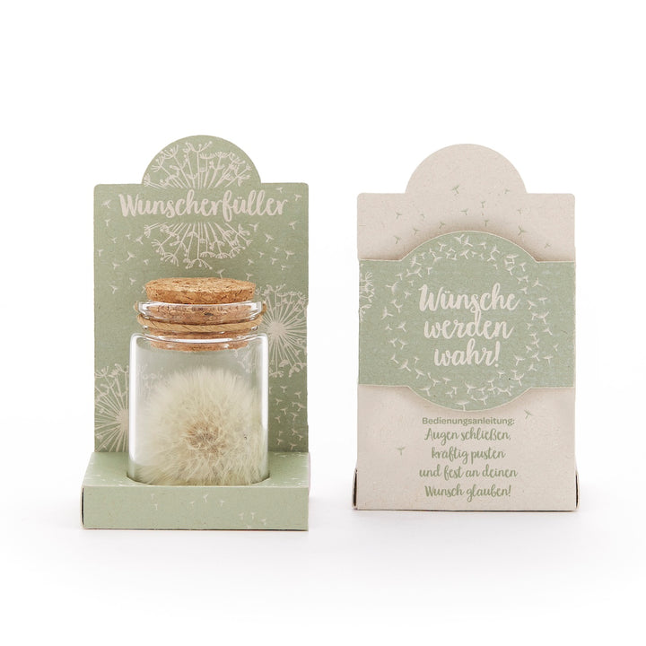 Zwei Verpackungen mit der Aufschrift "Wunscherfüller" und "Wünsche werden wahr"; eine enthält ein kleines Glasfläschchen mit einem Pusteblumen-Samenkopf und Korken.